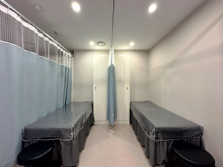Sala de Clínica de Mujeres S con dos camillas separadas por cortinas.